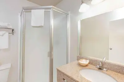 a bathroom with a shower and a sink and a mirror at Baymont by Wyndham Coalinga in Coalinga