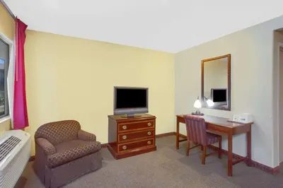 a hotel room with a desk and a television and a chair at Baymont by Wyndham Coalinga in Coalinga