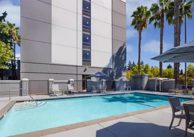 a swimming pool with chairs and a building at Hyatt Place Sacramento Rancho Cordova in Rancho Cordova