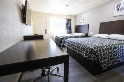 a hotel room with two beds and a table at Sky Riders Motel in Sacramento