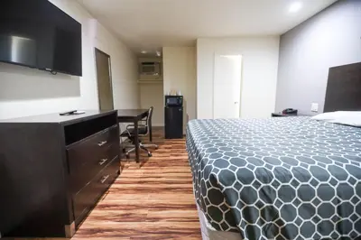 a hotel room with a bed and a desk and a television at Sky Riders Motel in Sacramento
