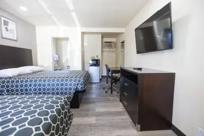 a hotel room with a bed and a desk with a television at Sky Riders Motel in Sacramento