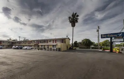 a parking lot in front of a hotel with a palm tree at Sky Riders Motel in Sacramento