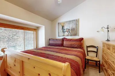 a bedroom with a bed and a chair and a window at Tavern Inn #55 in Olympic Valley