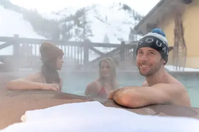 a man and two women in a swimming pool at The Village at Palisades Tahoe in Olympic Valley