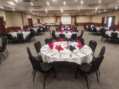 a large banquet hall with tables and chairs with red flowers at Wyndham Visalia in Visalia