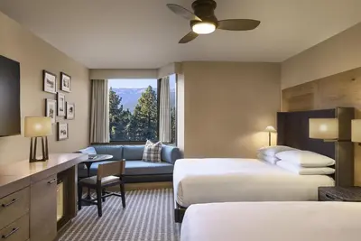 a hotel room with two beds and a couch at Hyatt Regency Lake Tahoe Resort, Spa & Casino in Incline Village