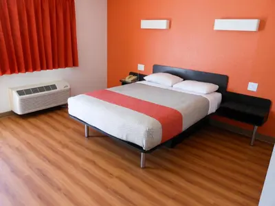 a bedroom with a bed with orange walls and wooden floors at Motel 6-Fallon, NV in Fallon