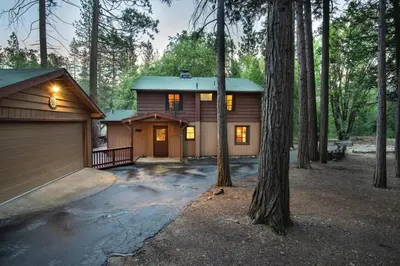 a house in the woods with a garage at Bassett's Cabin in Wawona