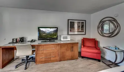an office with a desk with a television and a red chair at Angels Inn in Angels Camp