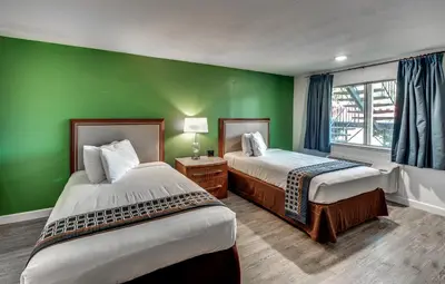 a room with two beds and a green wall at Angels Inn in Angels Camp