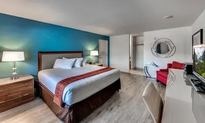 a hotel room with a bed and a flat screen tv at Angels Inn in Angels Camp