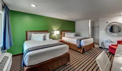 a hotel room with two beds and a green wall at Angels Inn in Angels Camp