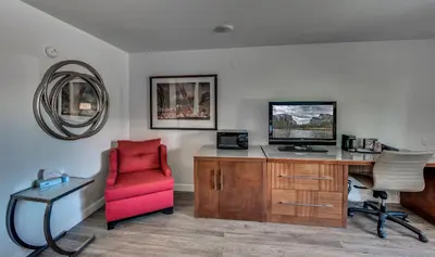 a living room with a desk and a red chair at Angels Inn in Angels Camp