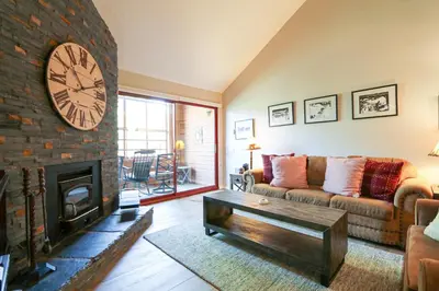 a living room with a large clock on a brick fireplace at Aspen Creek #306 Condo in Mammoth Lakes