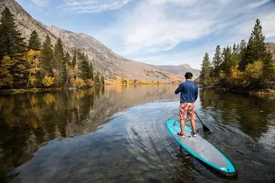 a man is standing on a paddle board in the water at Aspen Creek #306 Condo in Mammoth Lakes