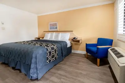 a hotel room with a bed and a blue chair at Budget Inn Corcoran Near Tulare CA 43 in Corcoran