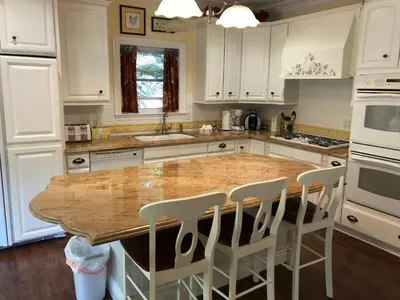 a kitchen with a wooden table and white cabinets at Carriage House at Yosemite in Fish Camp