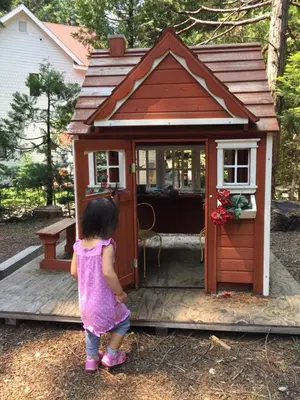 a little girl standing in front of a play house at Carriage House at Yosemite in Fish Camp