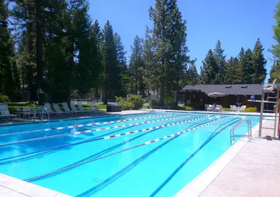 a large swimming pool with blue water and chairs at Sunny Daze at Dollar Point by Tahoe Getaways - Tahoe Classic w Open Floor Plan, Wood Fireplace, Close to Lake! in Tahoe City
