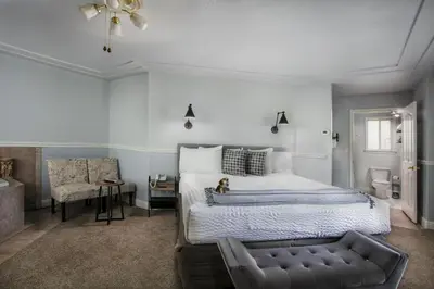 a bedroom with a large bed and a chair at Hounds Tooth Inn in Oakhurst