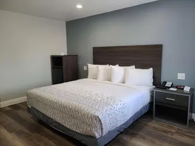 a bedroom with a large bed with a wooden headboard at SureStay Hotel by Best Western Chowchilla Yosemite in Chowchilla