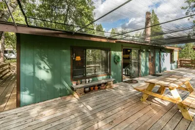 a green house with a bench on a deck at Yosemite Cabin in Wawona
