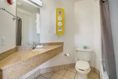 a bathroom with a toilet and a sink and a mirror at Howard Johnson by Wyndham Lemoore in Lemoore