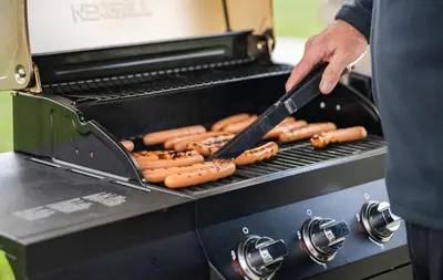 a man is cooking hot dogs on a grill at My Place Hotel-Carson City, NV in Carson City
