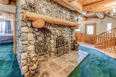 a stone fireplace in a room with a stone wall at Vienna Villa - 3 Bed 3 Bath Vacation home in Shaver Lake in Shaver Lake