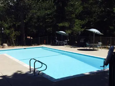 a blue swimming pool with chairs and umbrellas at Summit by 101 Great Escapes in Mammoth Lakes