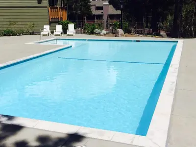 a large blue swimming pool with two chairs in it at Summit by 101 Great Escapes in Mammoth Lakes