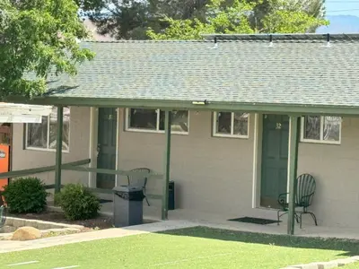 a house with a porch with a chair and a trash can at Lakeshore Lodge in Wofford Heights