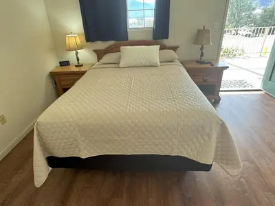a bed in a bedroom with two night stands and two lamps at Barewood Inn & Suites in Wofford Heights