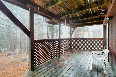 a porch of a cabin with a chair in the woods at Retro Family Gathering Home in Tahoe Donner in Truckee