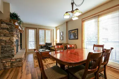 a living room with a wooden table and a fireplace at Mammoth Green #120 Condo in Mammoth Lakes