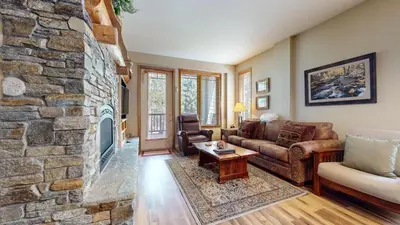 a living room with a stone fireplace at Mammoth Green #120 Condo in Mammoth Lakes