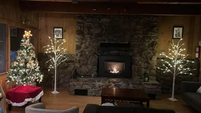 a living room with a stone fireplace and a christmas tree at The Mammoth Inn in Mammoth Lakes