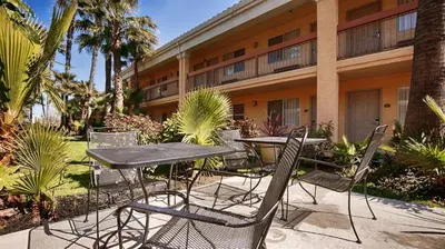 a table and chairs in front of a building at Best Western Palm Court Inn in Modesto