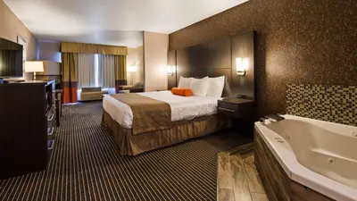 a hotel room with a bed and a bath tub at Best Western Plus Rama Inn & Suites in Oakdale
