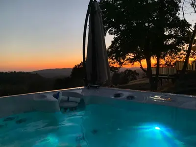 a swimming pool with an umbrella and a sunset at Moon Ranch - a gateway to Yosemite in Mariposa