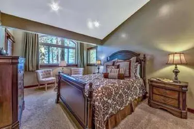 a bedroom with a bed and a table with a lamp at Lv12: luxury villa walk to the Beach in Glenbrook