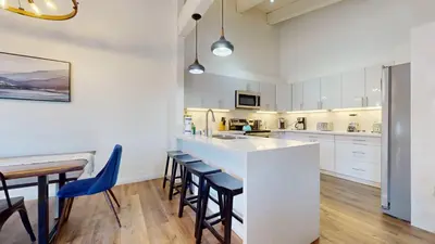 a kitchen with white cabinets and a bar with stools at Chateau De Montagne #6 Condo in Mammoth Lakes