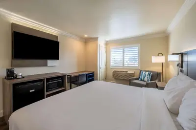 a hotel room with a large bed and a flat screen tv at Comfort Inn Gilroy in Gilroy
