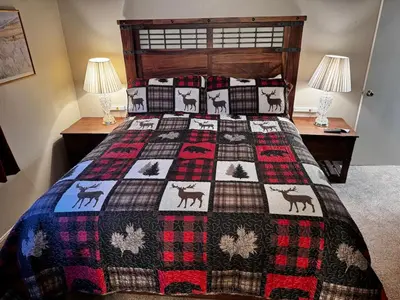 a bed with a quilt with deer on it at Mammoth Lakes Crestview Condo #50 in Mammoth Lakes