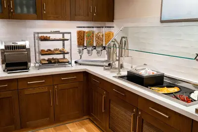 a kitchen with wooden cabinets and a counter with food at Homewood Suites By Hilton Rancho Cordova, Ca in Rancho Cordova