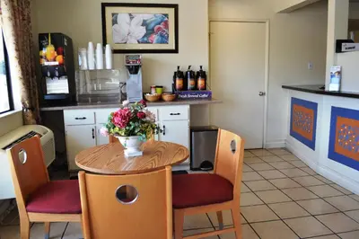 a kitchen with a table with a vase of flowers on it at Fresno Inn in Fresno