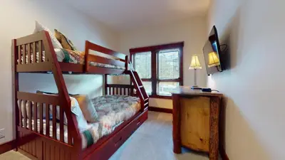 a bedroom with two bunk beds and a television at Juniper Crest #7 Condo in Mammoth Lakes