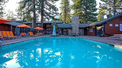 a large blue swimming pool in front of a cabin at 3 Peaks Resort & Beach Club in South Lake Tahoe