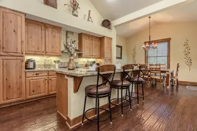 a kitchen with wooden cabinets and a table with bar stools at Lodges 1132 - 3 bedroom Townhome on Golf Course in Mammoth Lakes